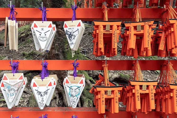 A collection of Japanese temple souvenirs featuring various types of Ema votive plaques, including wooden plaques designed in the shape of Torii