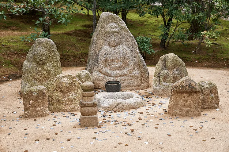 Jizo Buddhist images and coins that visitors tossed during the time of their visit to Kinkaku-ji, Kyoto, Japan