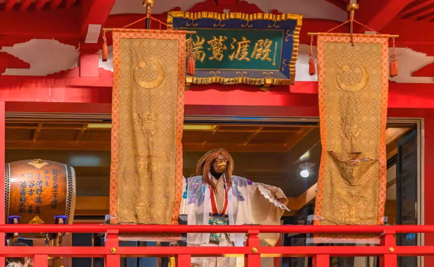 Japanese dancer in a kimono wearing a rooster mask performs a graceful kagura dance with a fan at Ootori Shrine during the lively Tori-no-Ichi festival